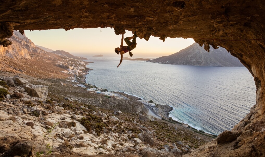 young-woman-climbing-in-cave-at-sunset-WCJVYR5